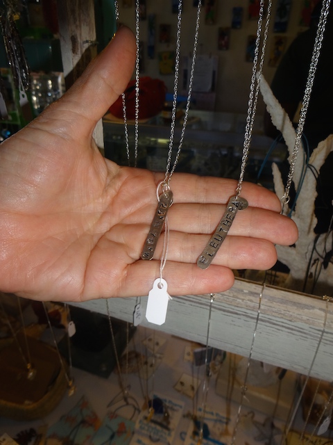 Pam's hand showing the silver necklaces with the map co-ordinates for Eleuthera